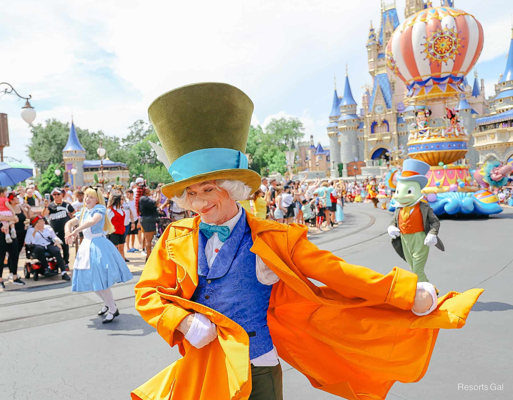 The Mad Hatter swings his bright orange coat to the side in the Festival of Fantasy Parade at Disney World. 