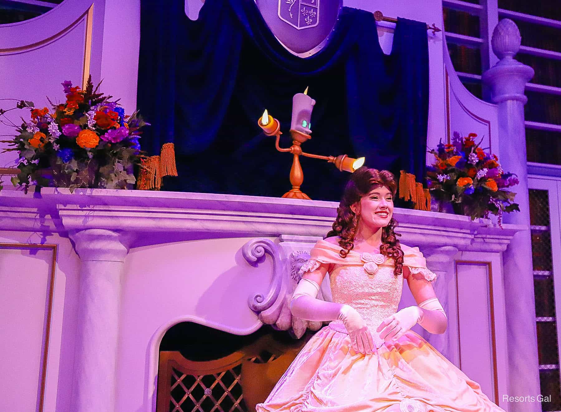 Belle smiles and Lumiere stands behind her in the Enchanted Tales with Belle attraction 