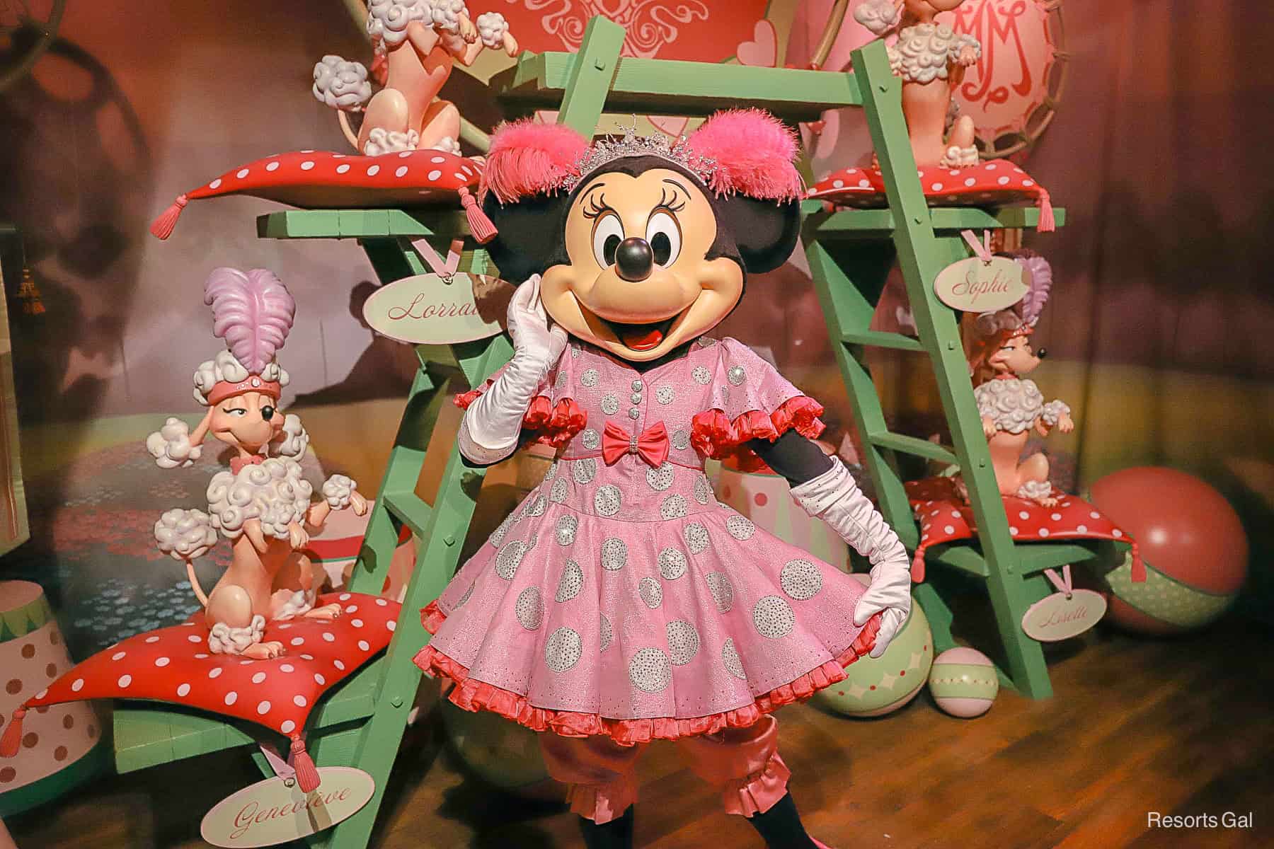 Minnie Mouse wears a pink dress with bows and pom pom's at Magic Kingdom.