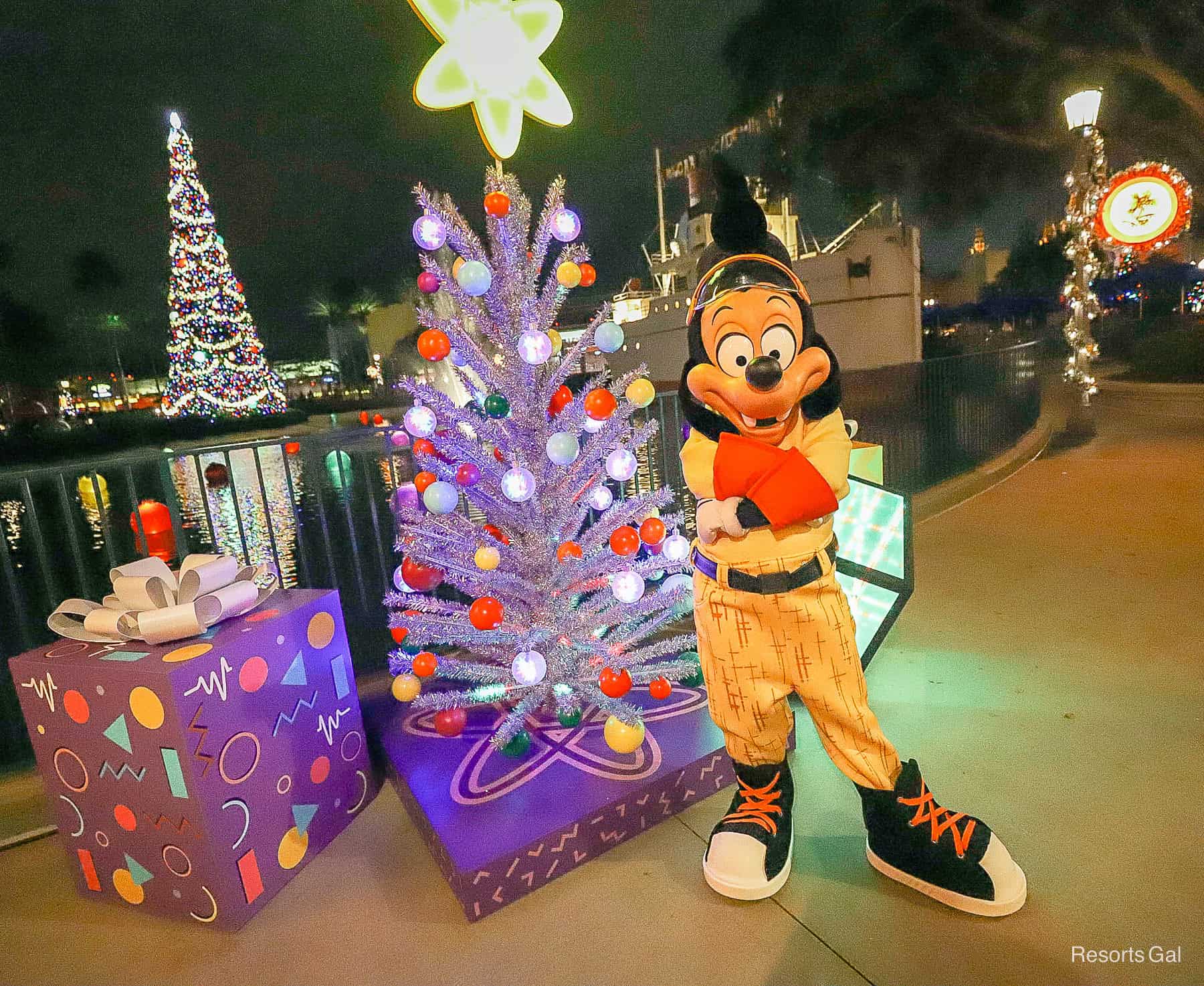 poses with elbows crossed in front of a Christmas scene at Echo Lake during Jollywood Nights