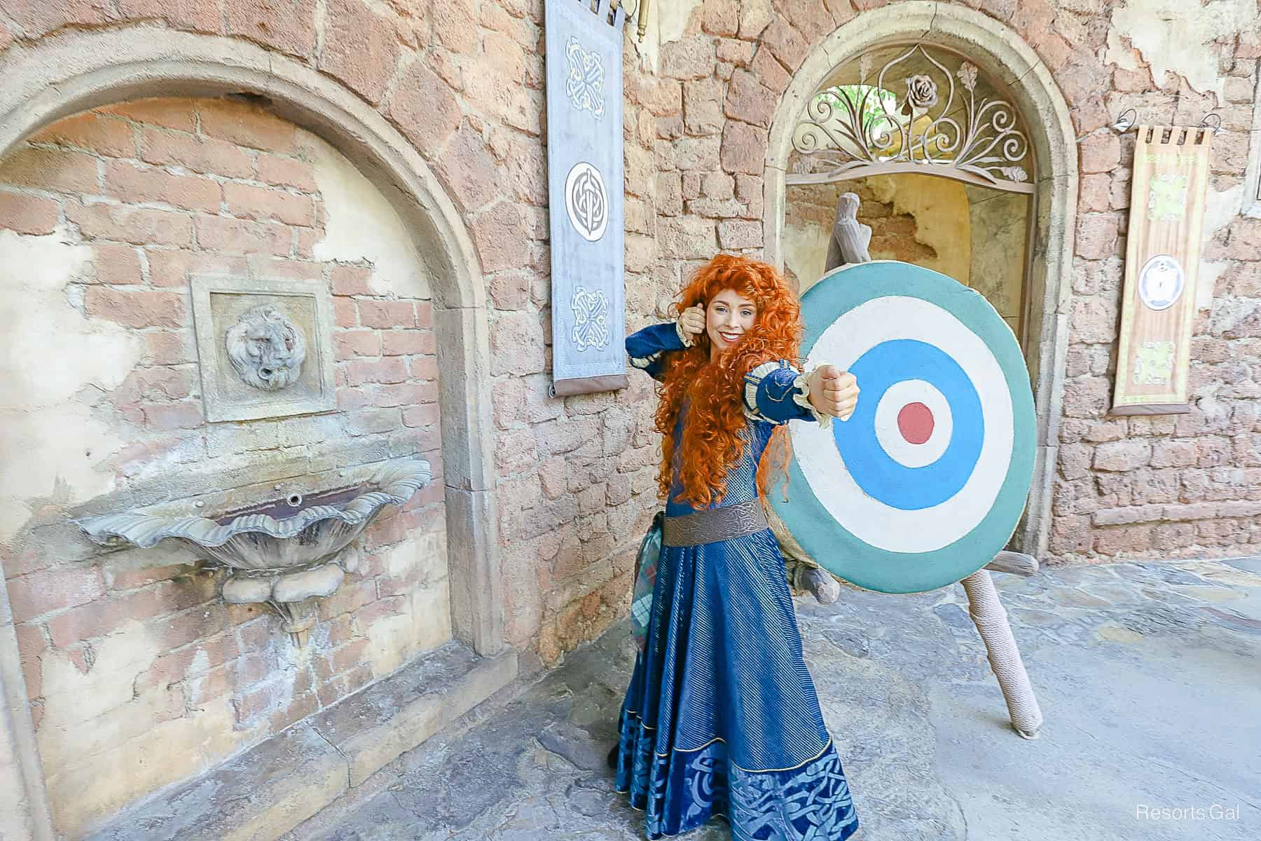 Merida poses like she's holding a bow and arrow. 