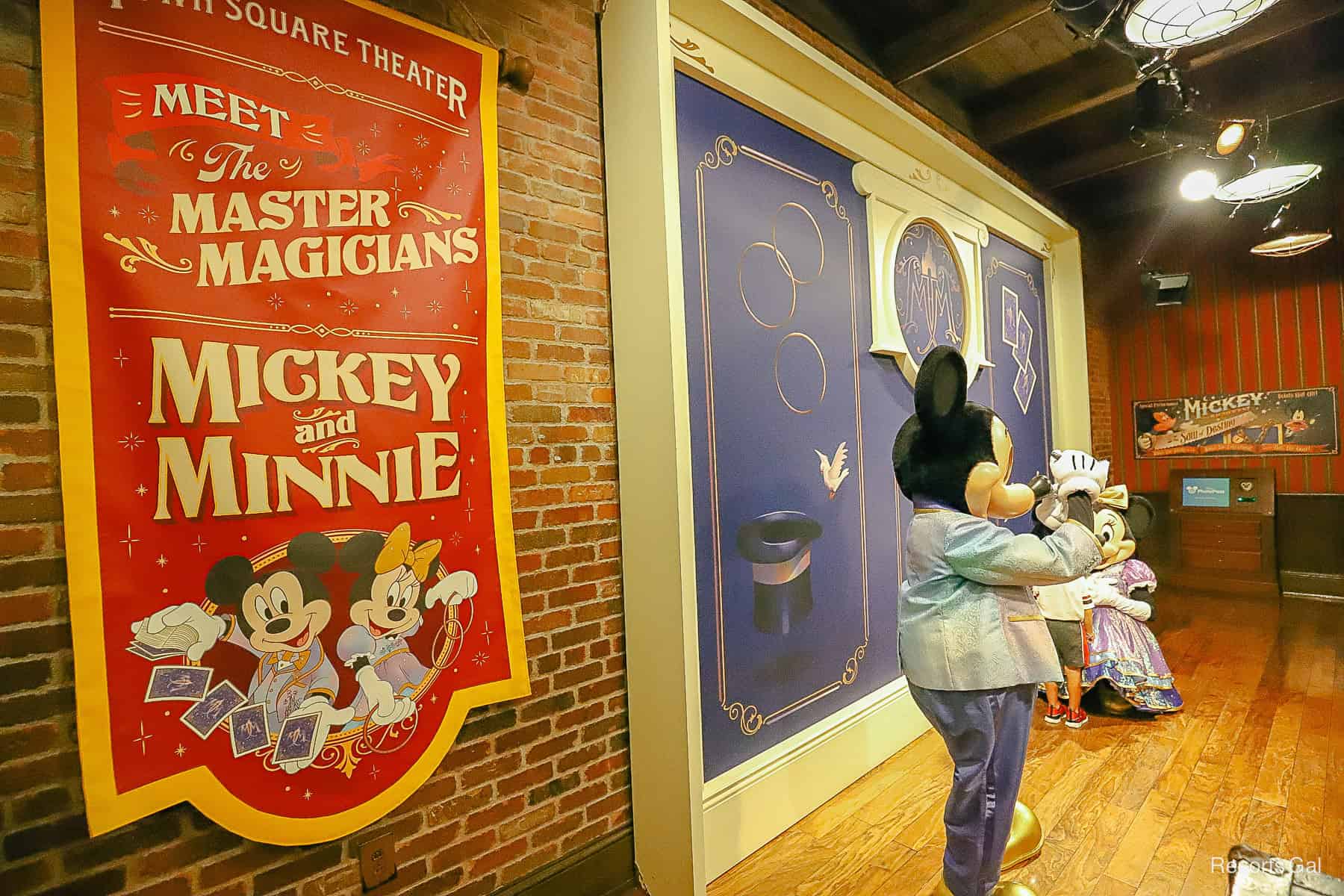 Mickey signing an autograph while Minnie talks with a guest. 