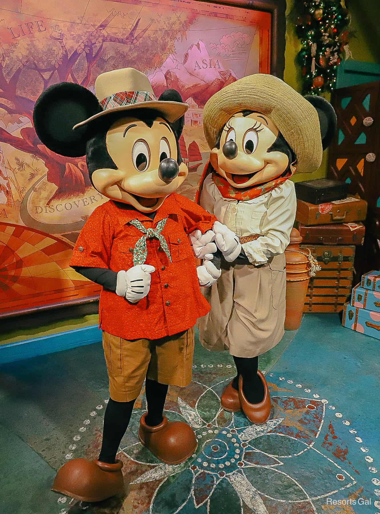 Minnie looks at Mickey. They are wearing safari outfits with holiday touches. 