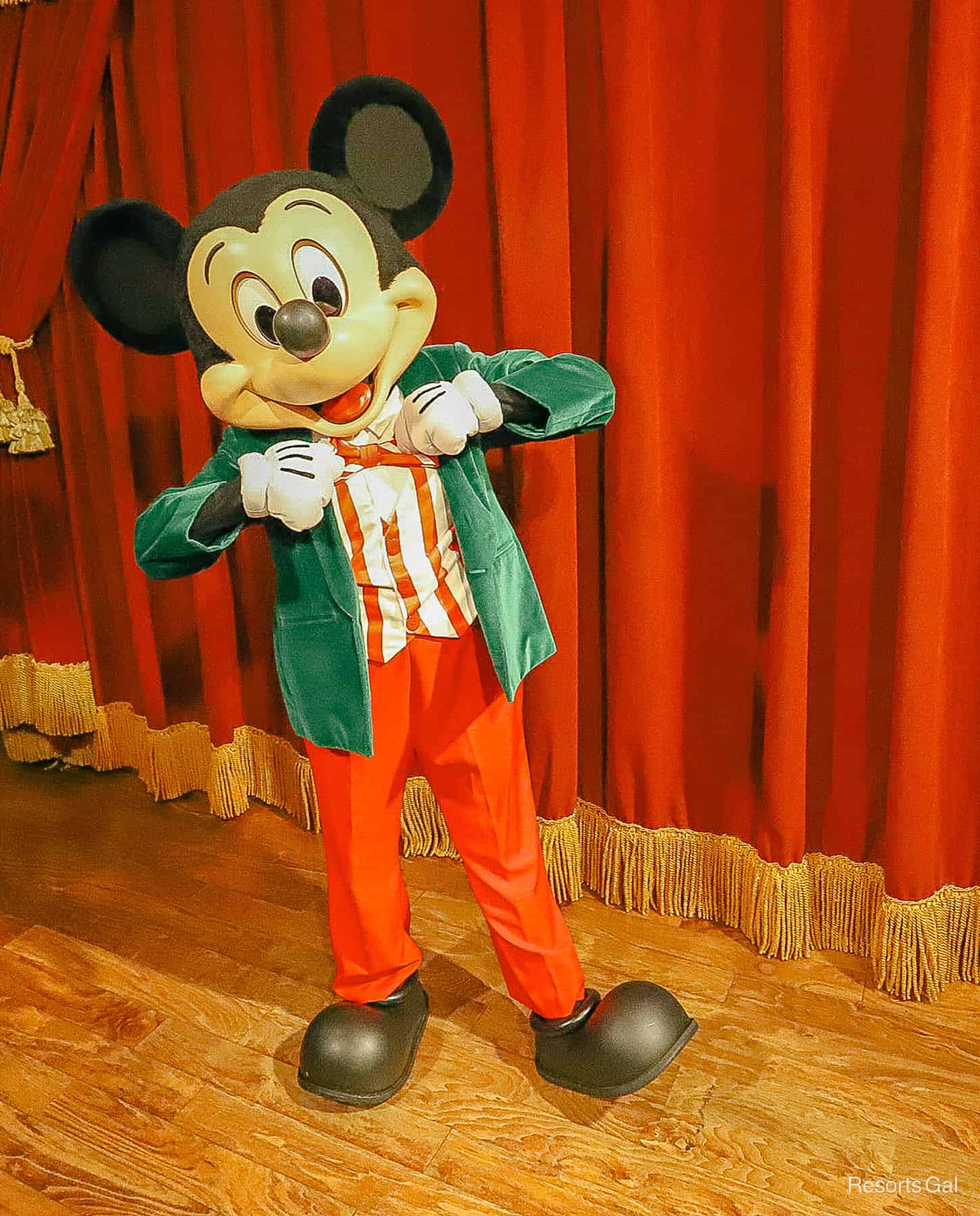 Mickey Mouse wearing a green velvet jack and red pants at Christmas. 