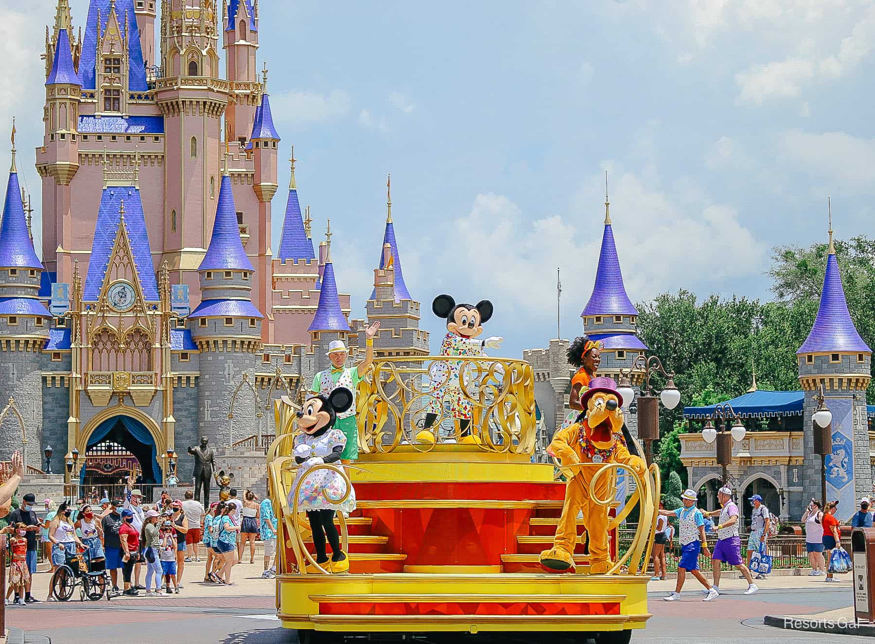 Mickey with friends on a parade float with Cinderella Castle behind them. 