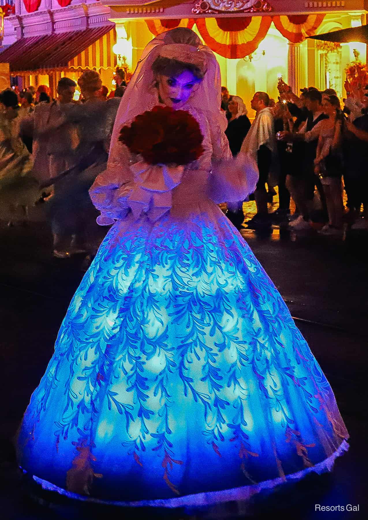 a ghost from the Haunted Mansion rolls through the parade in a brightly lit bridal gown 