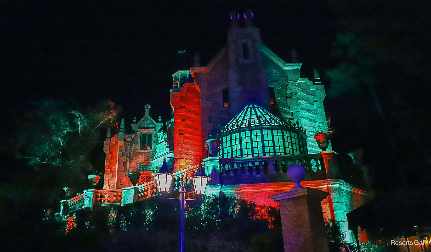 the Haunted Mansion with red and green lights at Mickey's Very Merry Christmas Party 