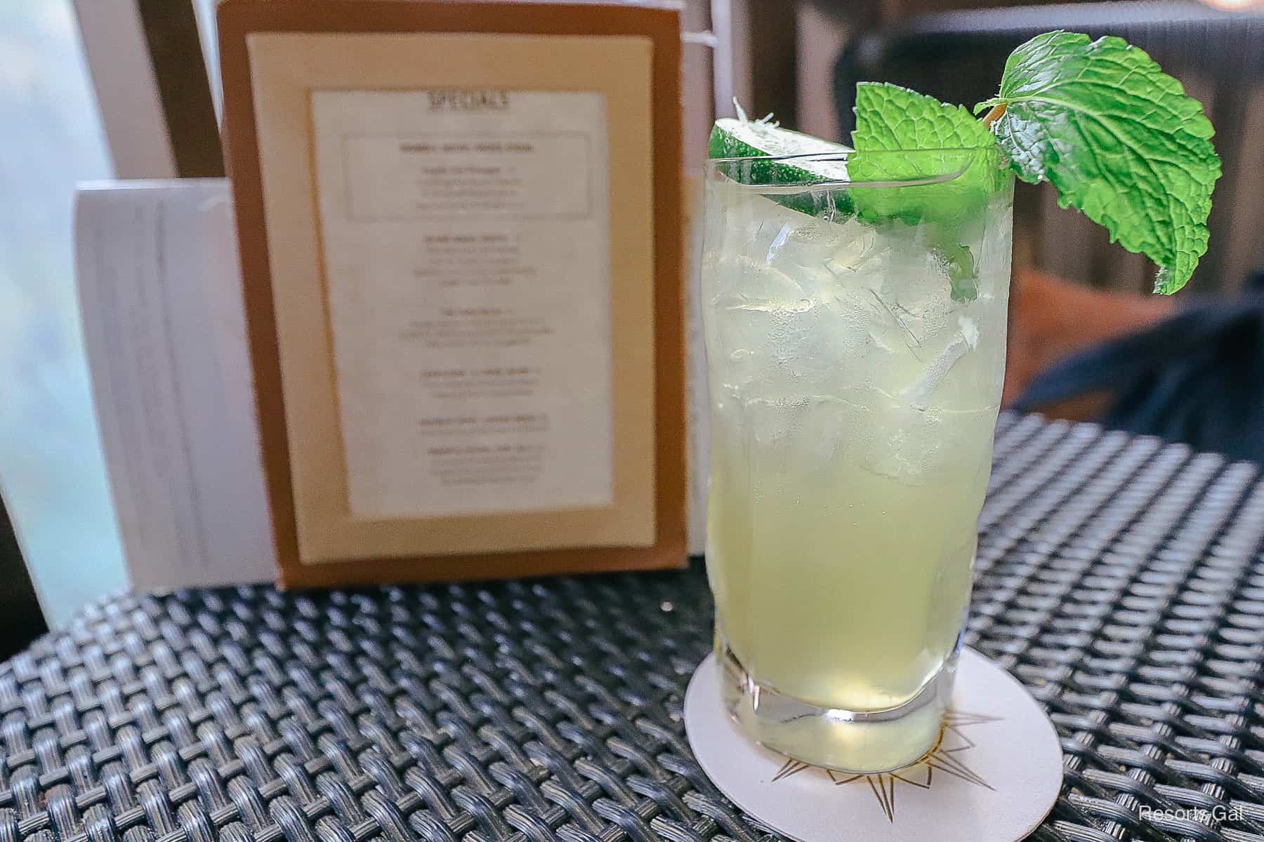 a light colored cocktail with a mint leave on top 