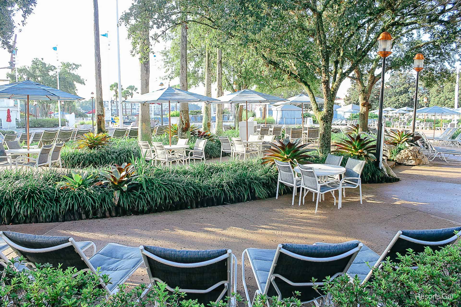 a cluster of tables covered with umbrellas and surrounded by trees near the pool area 