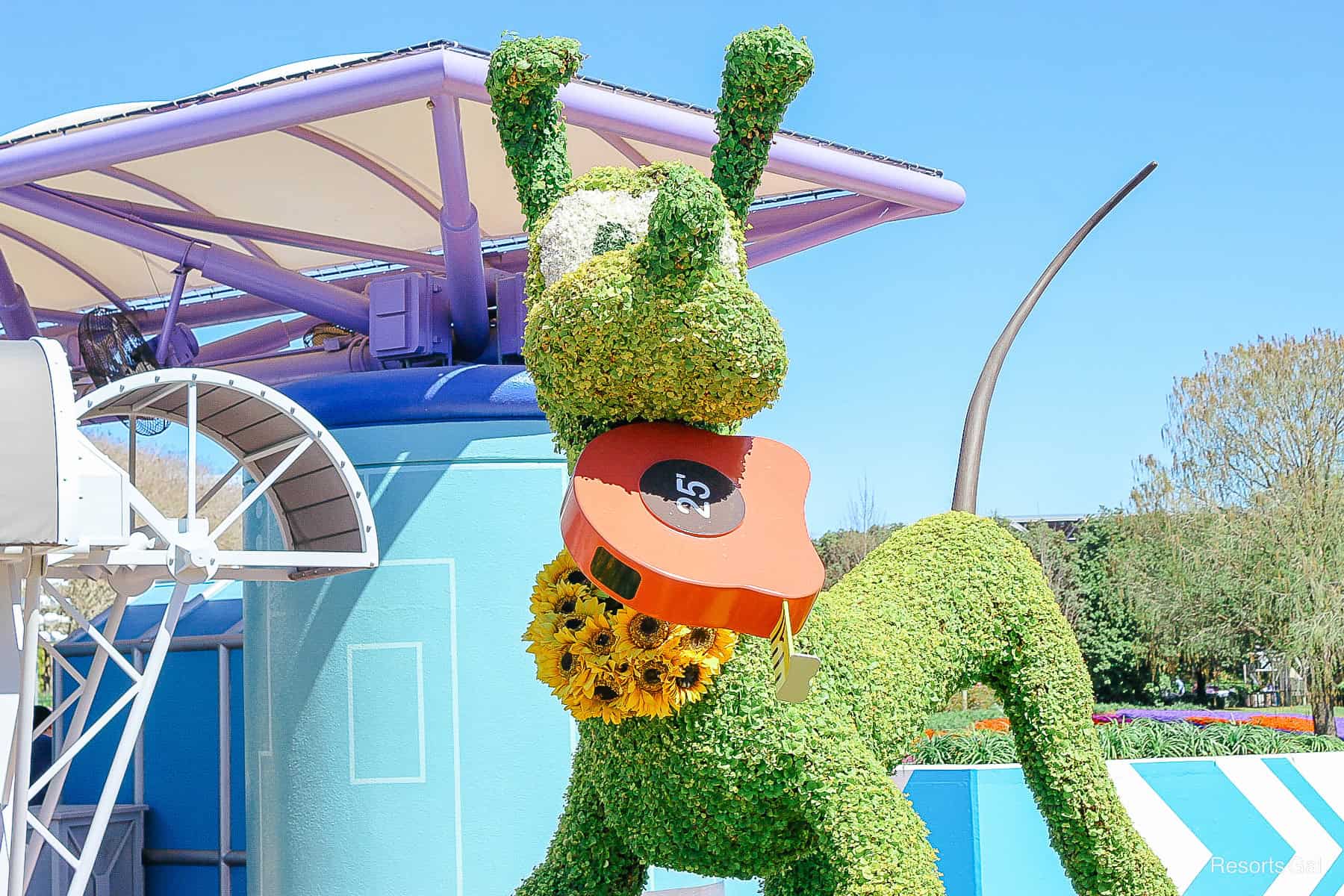 Pluto holds a tape measure in topiary form in 2021. 