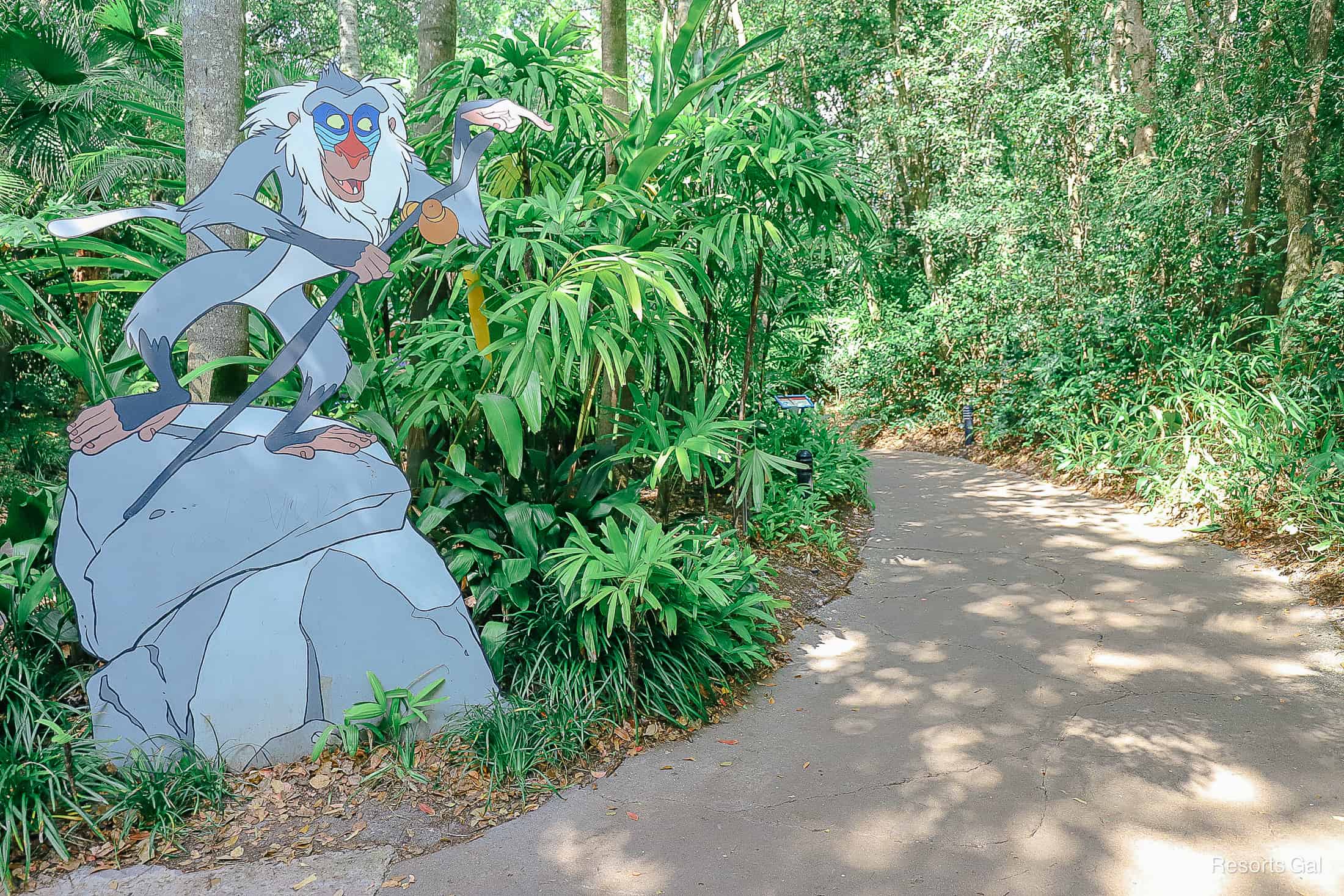 a painted cutout of Rafiki points guests down the path to Rafiki's Planet Watch 