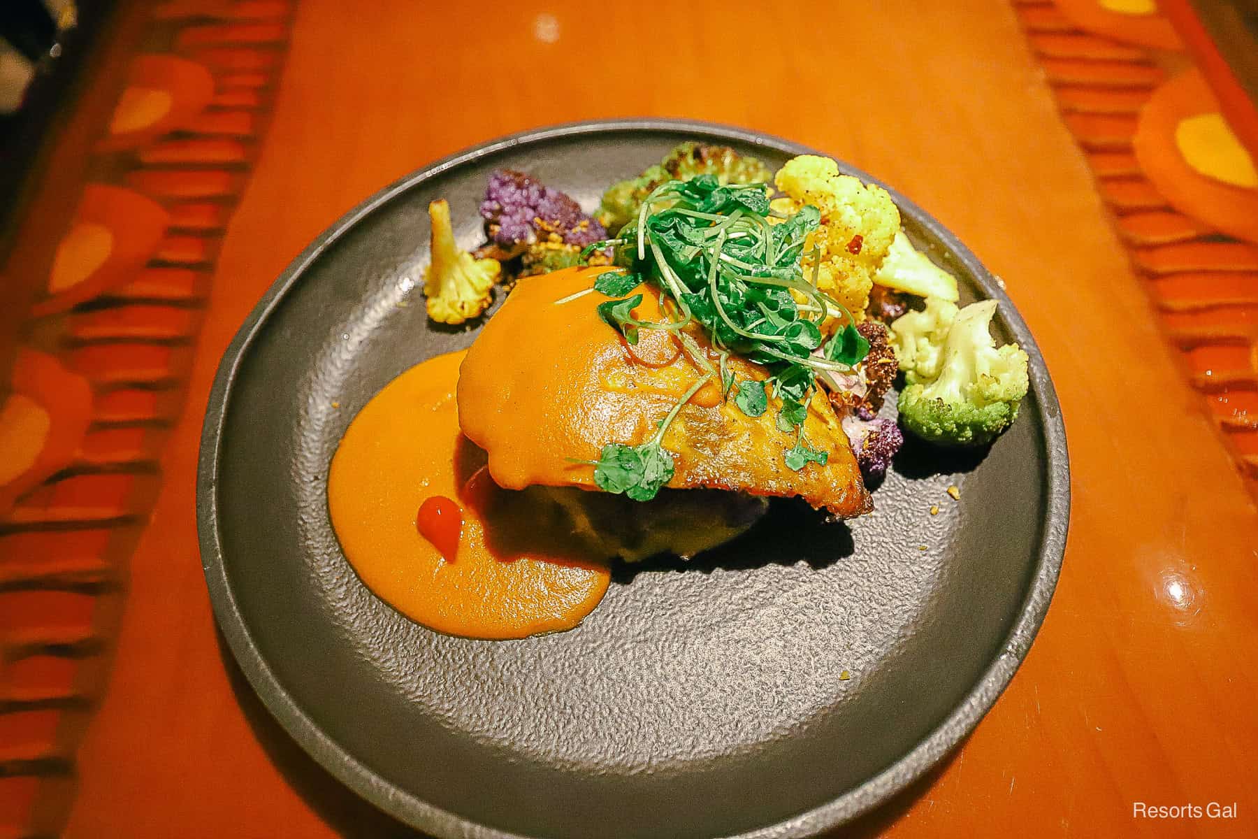 a dish with vegetables and a sustainable fish covered in curry sauce from Sanaa a Disney Hotel Restaurant 