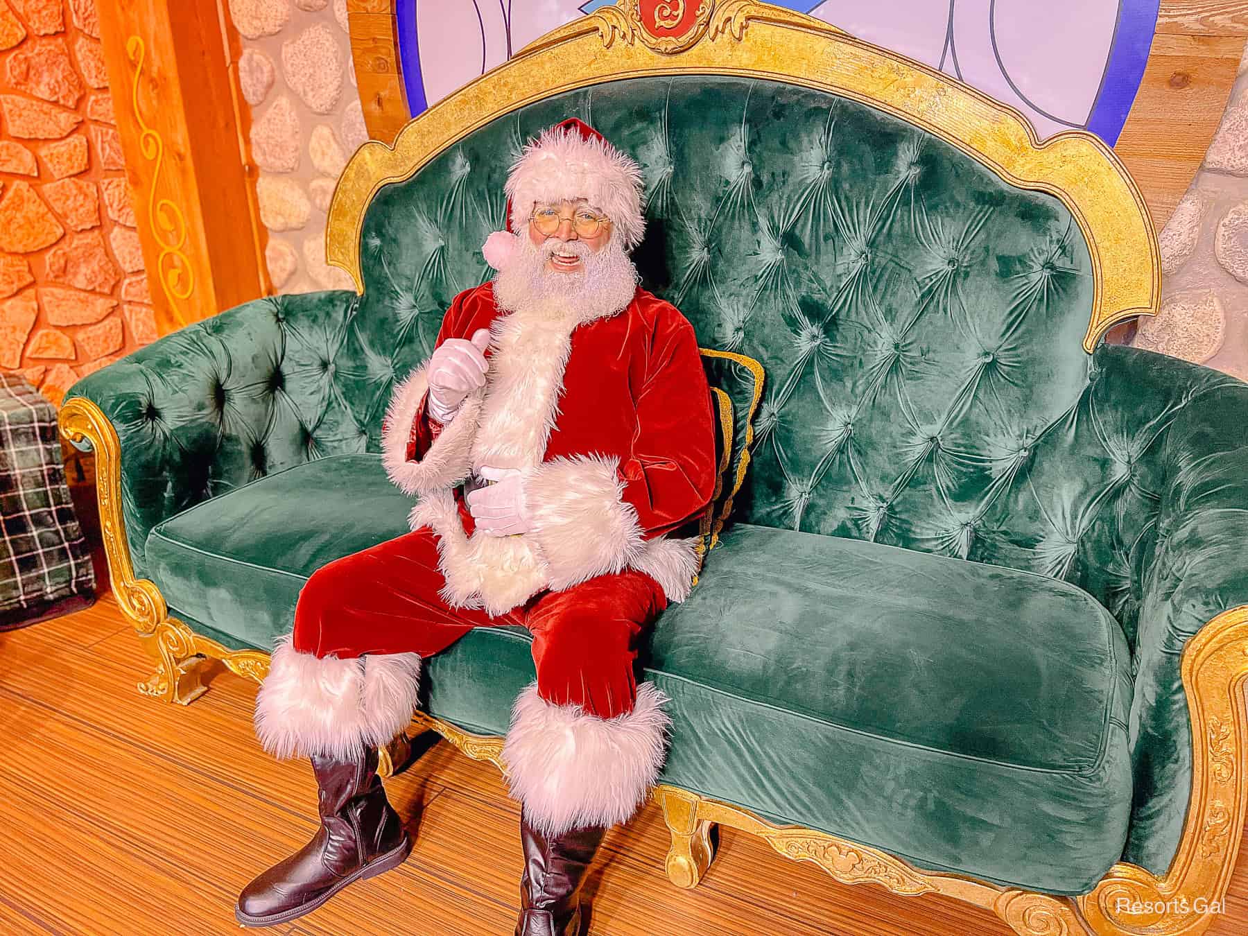 Santa Claus sitting on a green velvet sofa. 