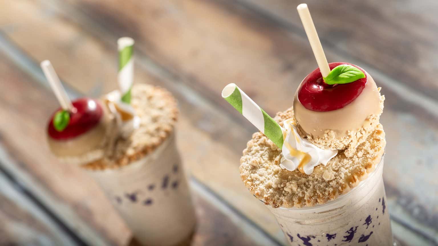 caramel apple milk shake topped with a candy apple covered in caramel with green and white straw 