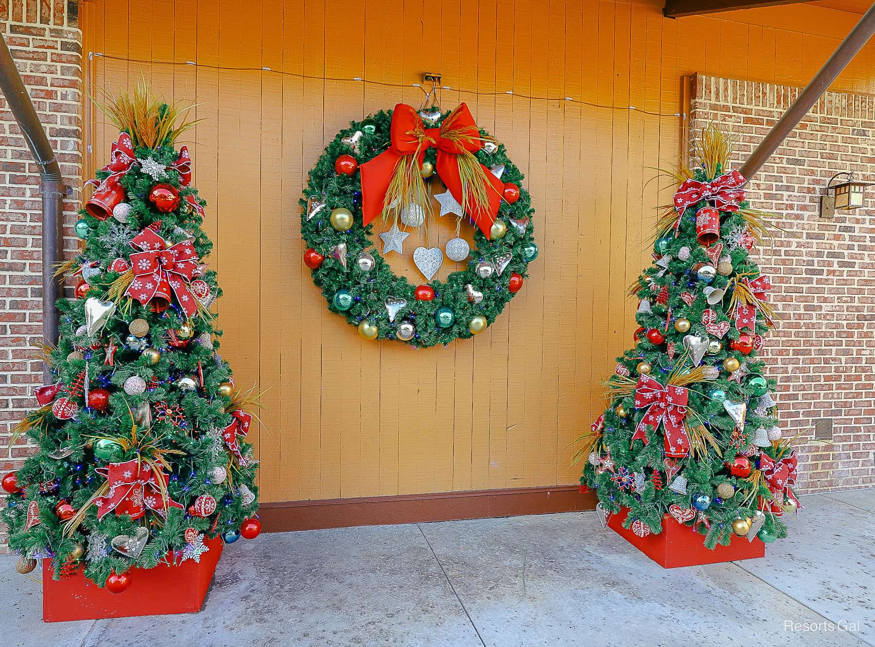 two Christmas trees with a wreath between them 