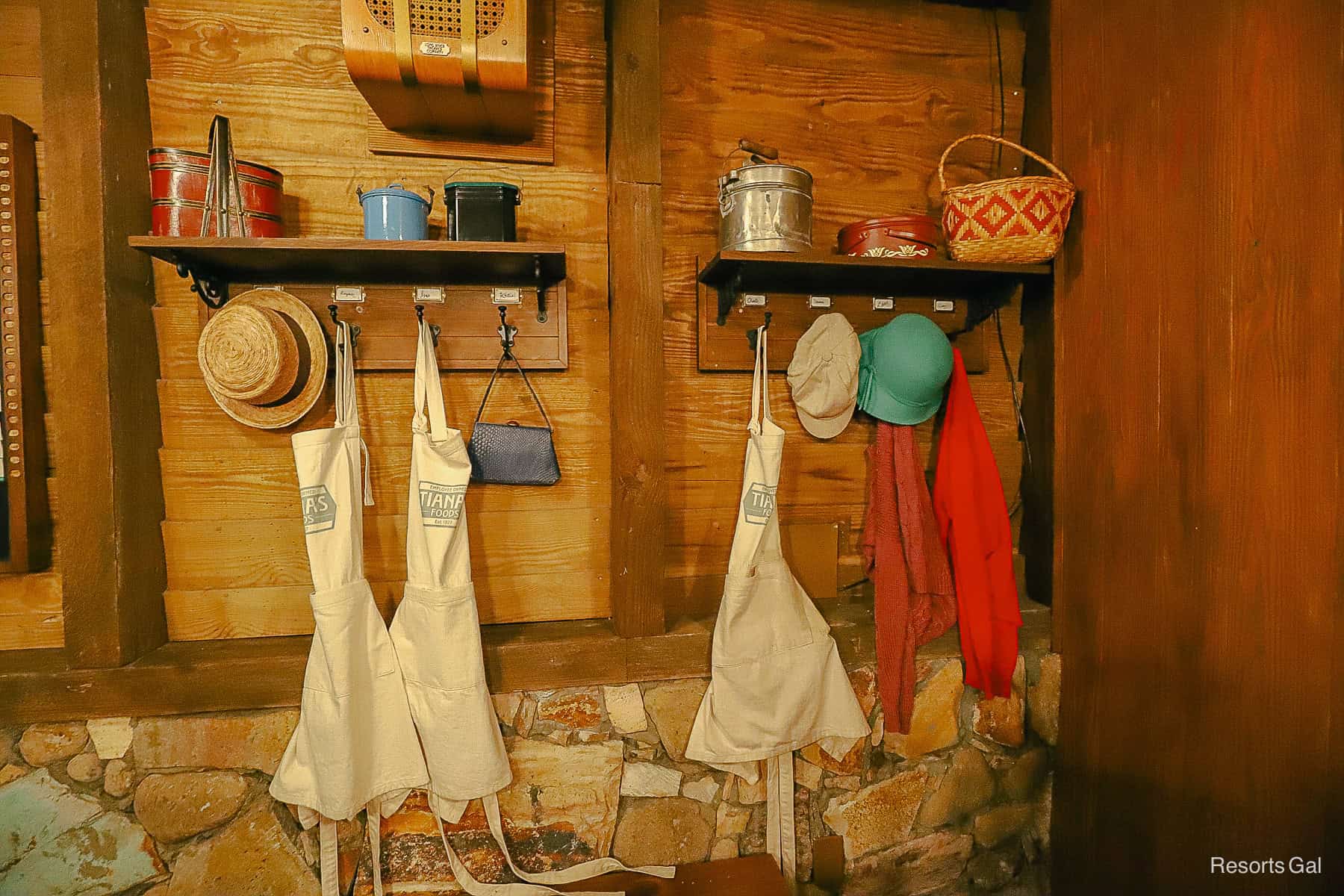 Tiana's Food aprons, hats, and baskets hanging in the queue portion of Tiana's Bayou Adventure 